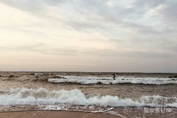 高清摄影 海洋中一个骑着冲浪板的人在波浪上。