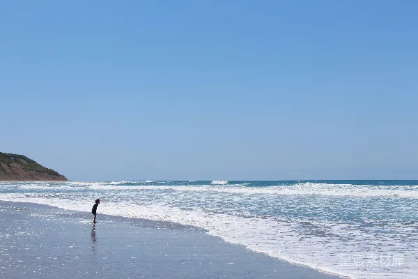 高清摄影 海边的孩子站在那里面向奔涌的海浪。