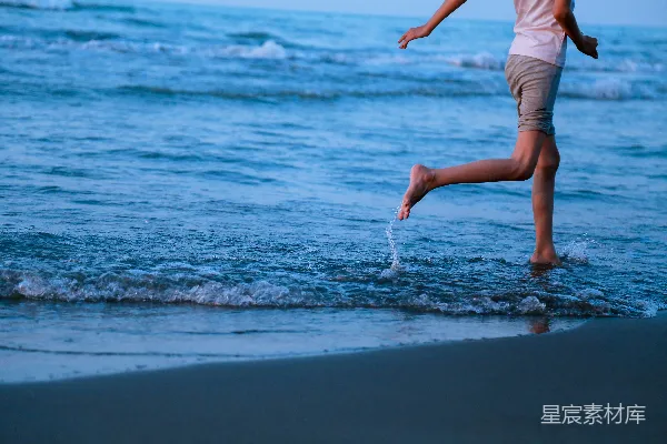高清摄影 海滩上有一位女士在水中奔跑。