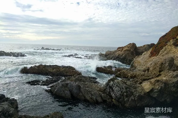 高清摄影 棕色的岩石海岸在白天的白云下被海浪覆盖