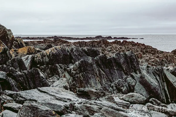 高清摄影 一片岩石嶙峋的岸边，远处有一片水域。