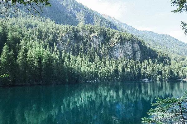 高清摄影 近水处有绿色的松树，距离山峦很远。