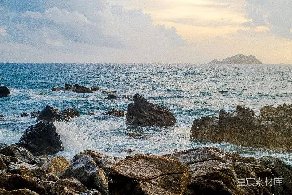 高清摄影 白天岩石海岸上有波浪，白云下阳光照射着。