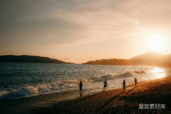 高清摄影 海边的人们在日落时散步。