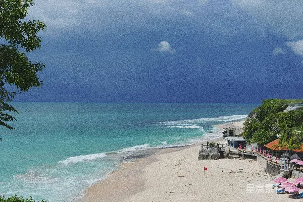 高清摄影 海滩上的景色，有遮阳伞，天空中有云。