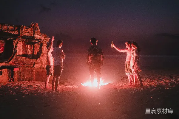 高清摄影 一群人在海滩岸边在夜间站立。