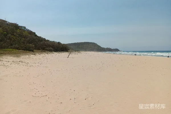 高清摄影 背景中有座小山的金色沙滩