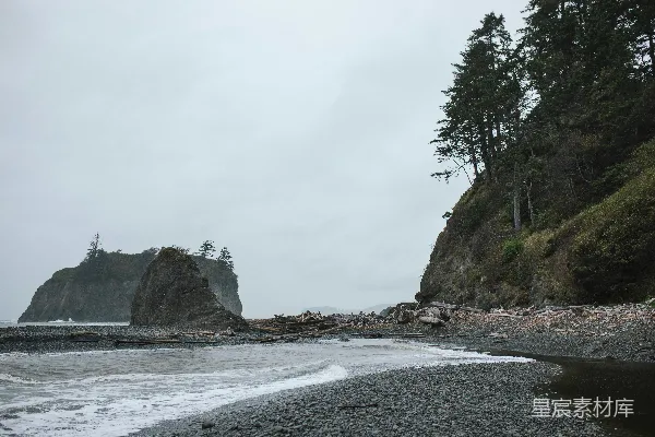 高清摄影 一片岩石海滩，背景中有巨大的岩层形成。
