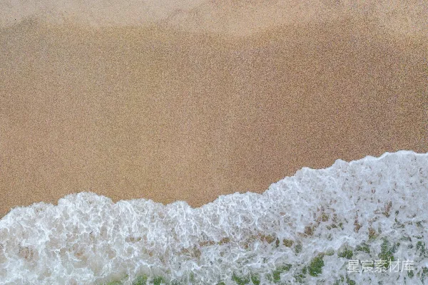 高清摄影 一个男人骑在冲浪板上，漂浮在覆盖着沙滩的波浪之上。