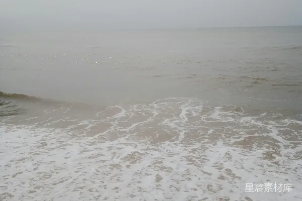 高清摄影 一片沙砾海滩，海浪涌向岸边