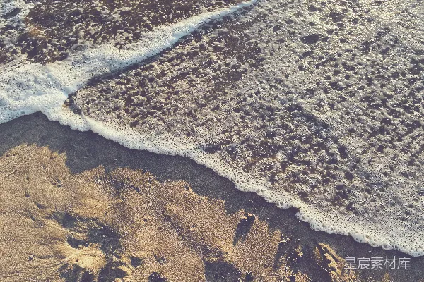 高清摄影 一片海滩的空中视角，沙滩上泛着波浪。