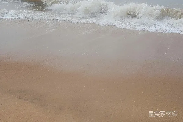 高清摄影 一片沙滩，海浪涌向岸边。