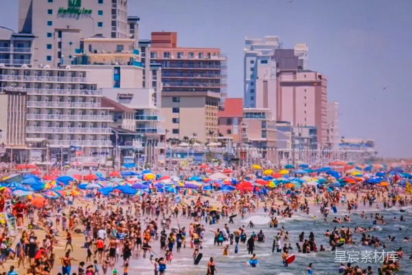 高清摄影 海滩上一群人的场景中，有遮阳伞。