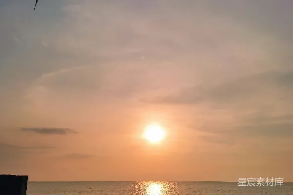 高清摄影 海边的太阳正落下到带着伞的沙滩上。