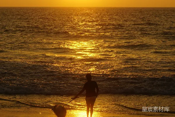 高清摄影 一个人在海滩上晒着夕阳，一条狗也在旁边。