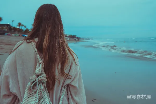 高清摄影 一个女人在海滩上拿着手提包散步。