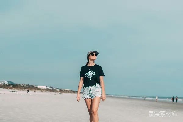 高清摄影 黑白T恤和蓝色牛仔短裤的女人站在海滩上，白天时间。