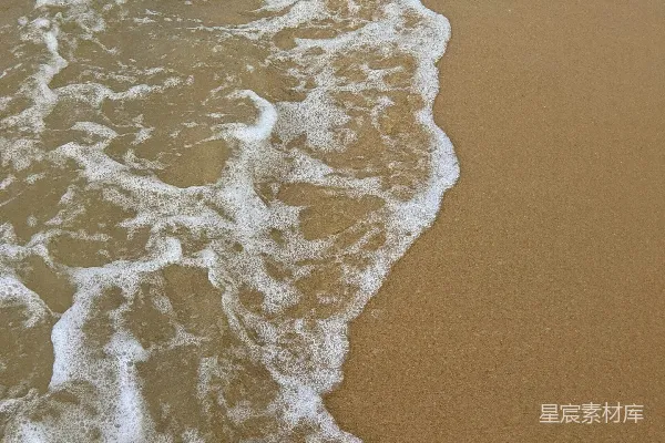 高清摄影 一片细软的沙滩，海浪涌向岸边。