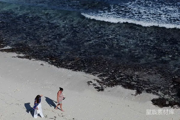 高清摄影 一群人在海边沿着沙滩行走，靠近大海