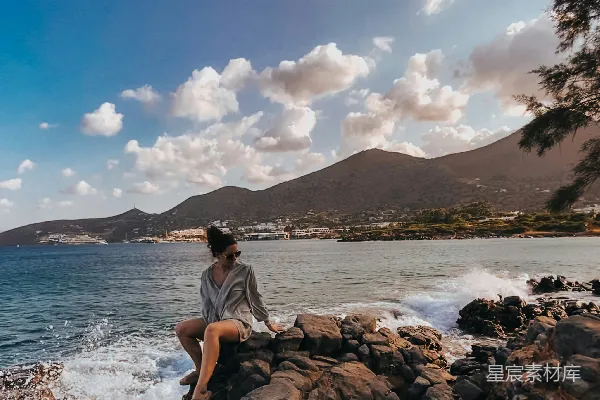 高清摄影 一个女人坐在海边的一块岩石上。
