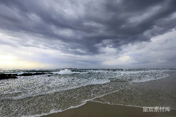 高清摄影 海滩上的多云天气，海浪涌来。