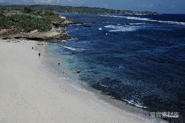 高清摄影 海边有人在沙滩上行走，旁边是大海