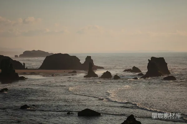 高清摄影 海边一块岩石嶙峋的海滩，在背景中有一片水面。