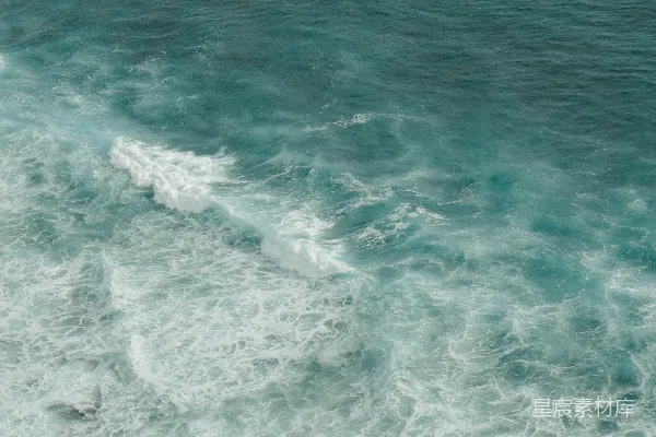 高清摄影 一个男子骑在波浪上的冲浪板上，漂浮在覆盖着海水的大海上。