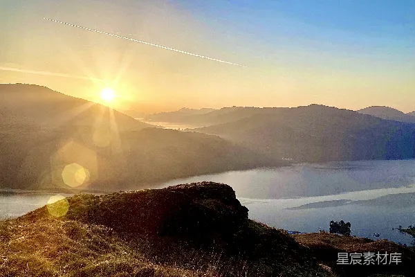 高清摄影 背景中有山丘和一片水面，夕阳在天边。