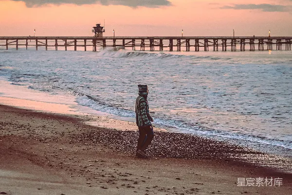 高清摄影 黑白衣裙的女人站在海滩上，夕阳西下。