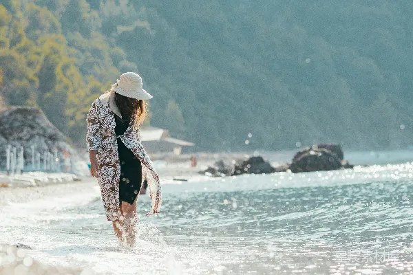 高清摄影 一位妇女沿着海边漫步，旁边是海洋。