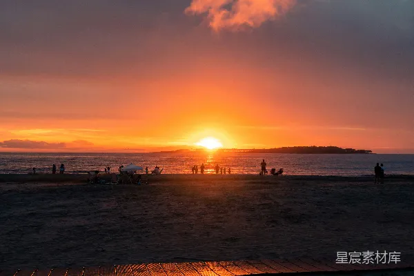 高清摄影 夕阳西下，海边有人行走。