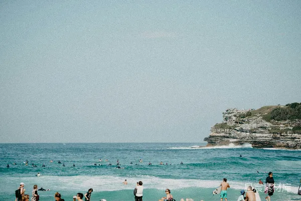 高清摄影 一群人在海边的沙滩上站立，靠近大海。