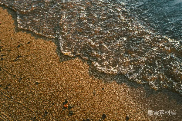 高清摄影 沙滩上沙粒堆积着，波浪涌向岸边。