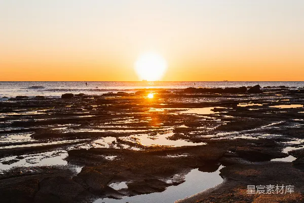 高清摄影 夕阳西下，海天相接处点缀着岩石。