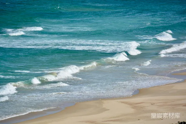高清摄影 海边的一片海滩景象，海浪自海洋涌来。