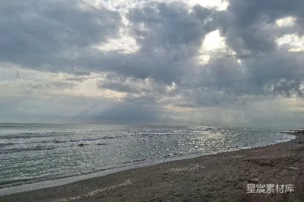 高清摄影 海边沙滩旁边，天空阴沉的一片。