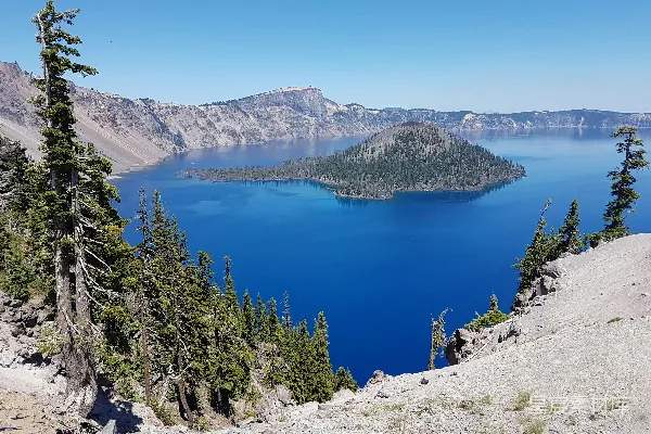 高清摄影 绿松树环绕在蓝湖附近的一座白岩石山的白天景色