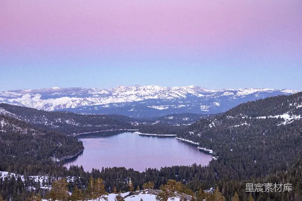 高清摄影 被雪覆盖的山峦环绕着的一片湖泊在粉红色的天空下。
