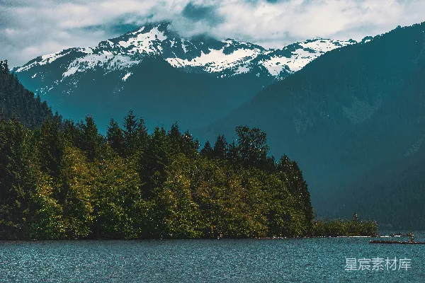 高清摄影 一个被树木环绕的湖泊，在其背景中有一座山峰。