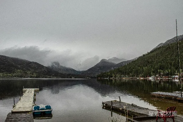 高清摄影 白蓝相间的船停泊在湖边，近处有绿树和山峦，在白天的景象。