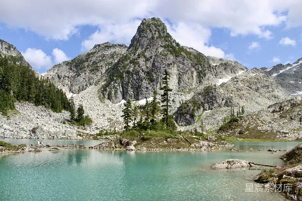 高清摄影 绿湖周围是绿色的树木和灰色的山，在蓝天白云下白天景象