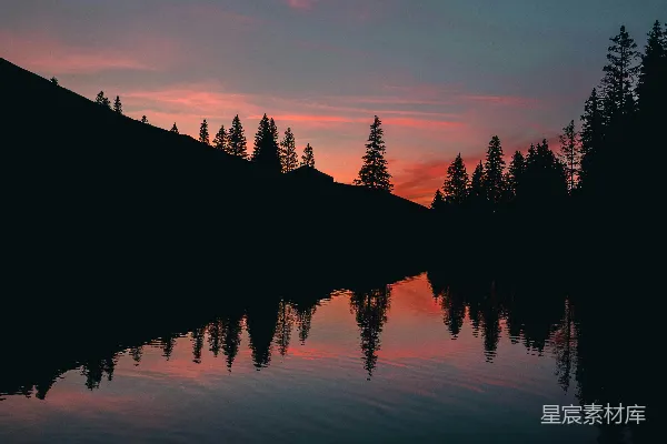 高清摄影 夕阳落下一片湖畔，背景是树木。