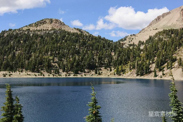 高清摄影 一片被树木和山峦环绕的湖泊在蓝天之下。
