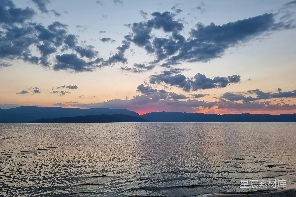 高清摄影 夕阳西下，海天相接处有远处的山峦。