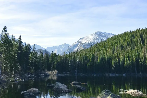 高清摄影 一个被森林环绕的湖泊，山峦在背景中。