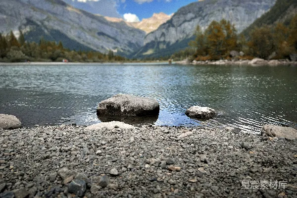 高清摄影 海边一块岩石地带旁边有水体，背景是山脉。