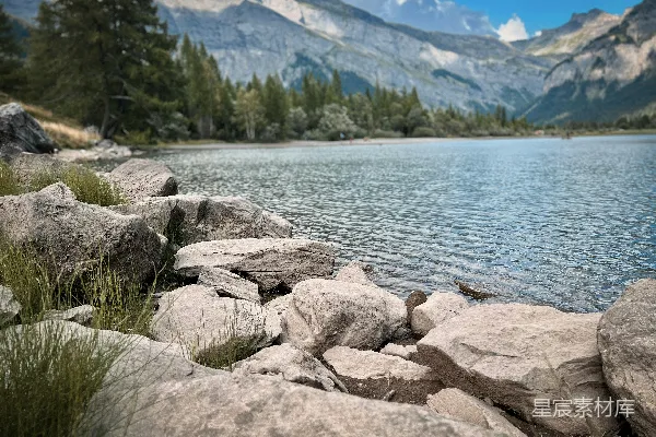 高清摄影 一片岩石嶙峋的海岸线，背景是湖泊和山脉。