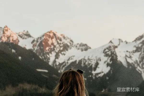 高清摄影 一个女人站在湖边，背景是山脉。