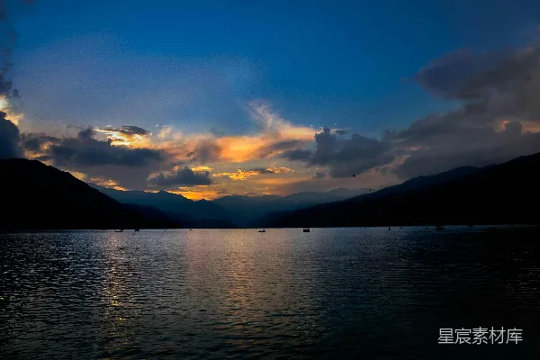 高清摄影 夕阳落下一片湖畔，背景是山峦。